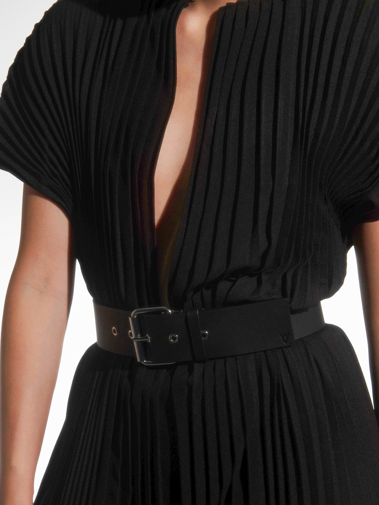 a close-up of a black maxi wrinkle-resistant hand-pleated dress with a slit in the front, with black yvy buckle belt on the waist