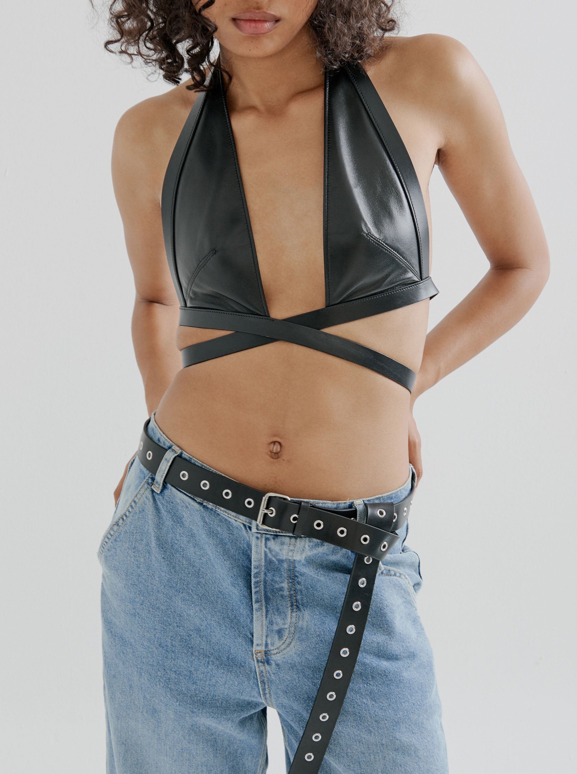 a closeup of a female model wearing black yvy leather wrap bra and a black yvy eyelet belt