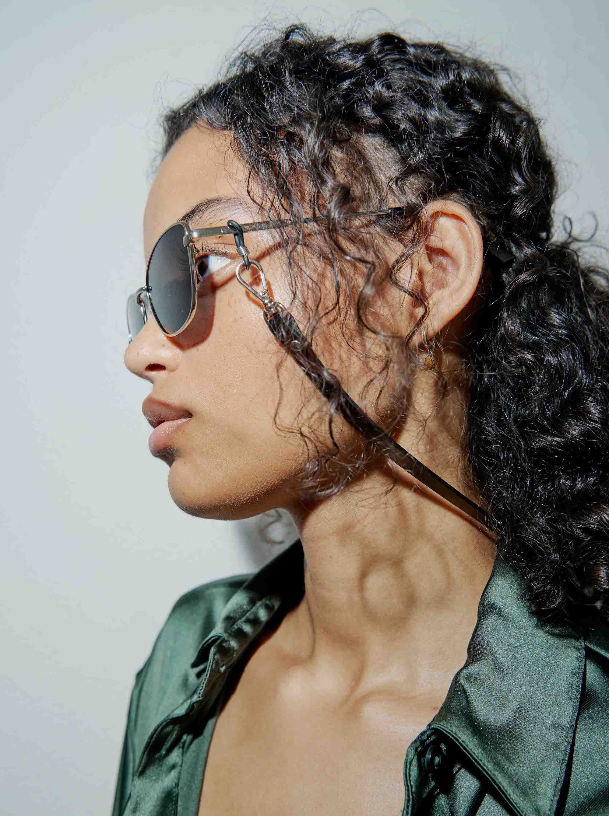 side view of yvy leather neck strap with gold hardware attached to sunglasses