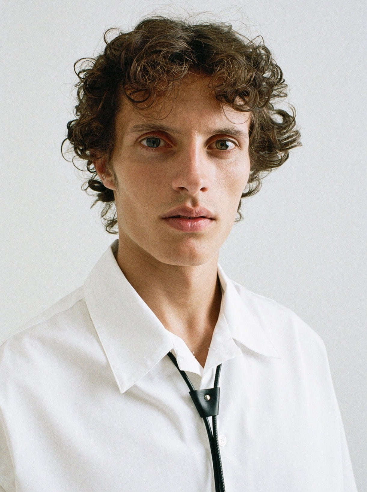 closeup of man wearing yvy leather black bolo choker over white shirt