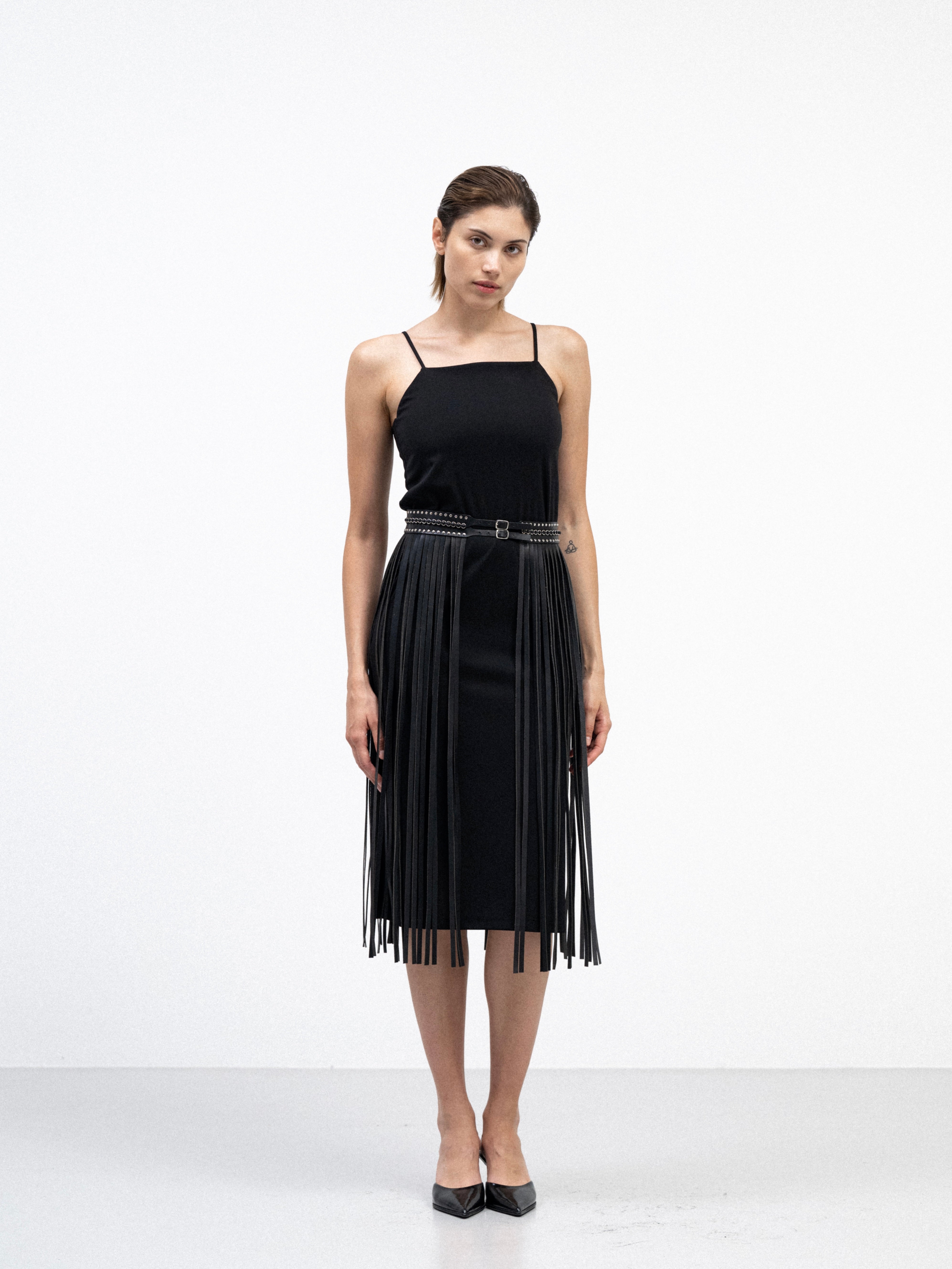 a female model wearing handmade black yvy long fringe belt with silver hardware and long leather strips over the midi black dress