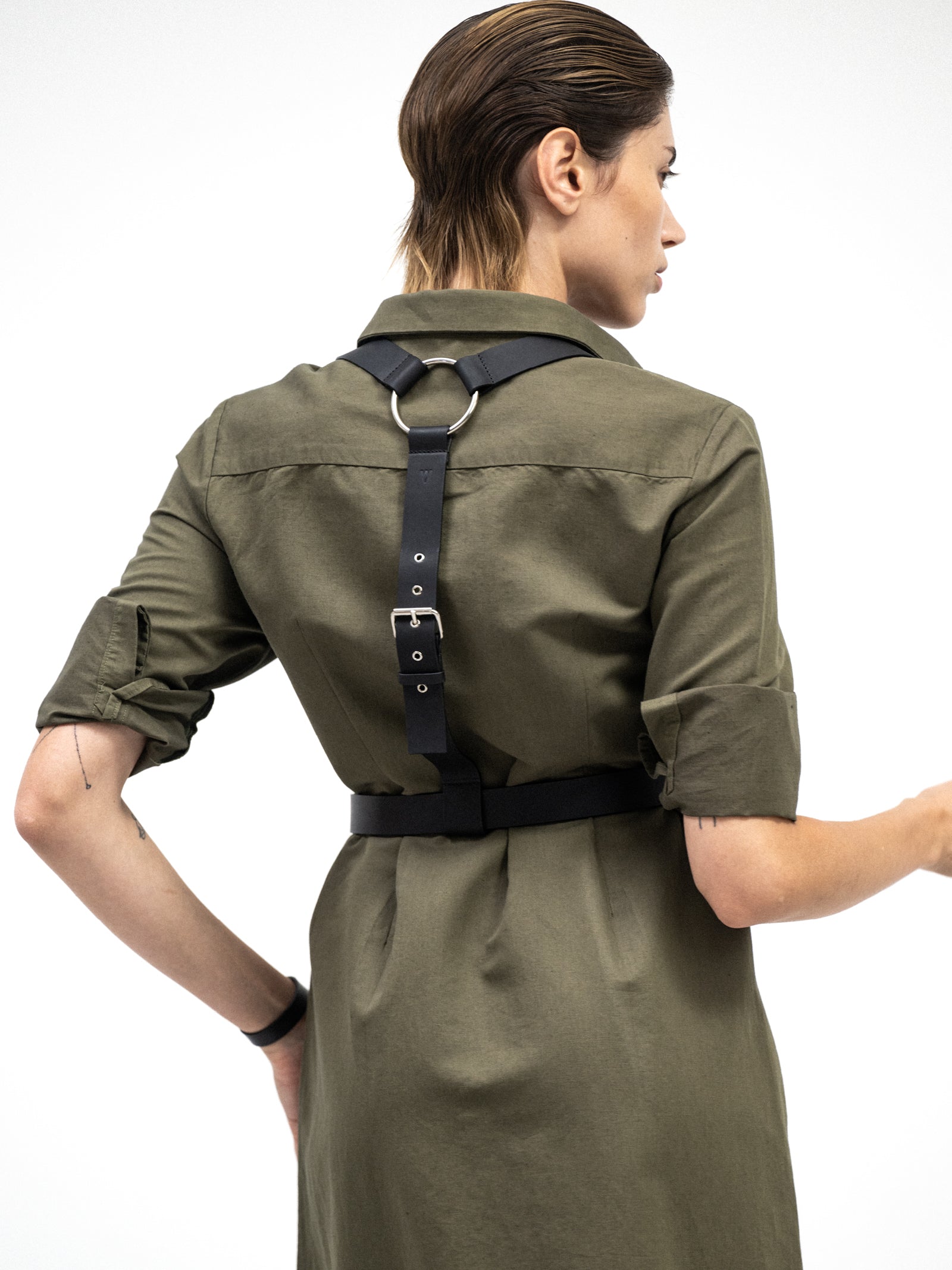 back view of a model wearing the green linen shirt dress with the belt harness short version