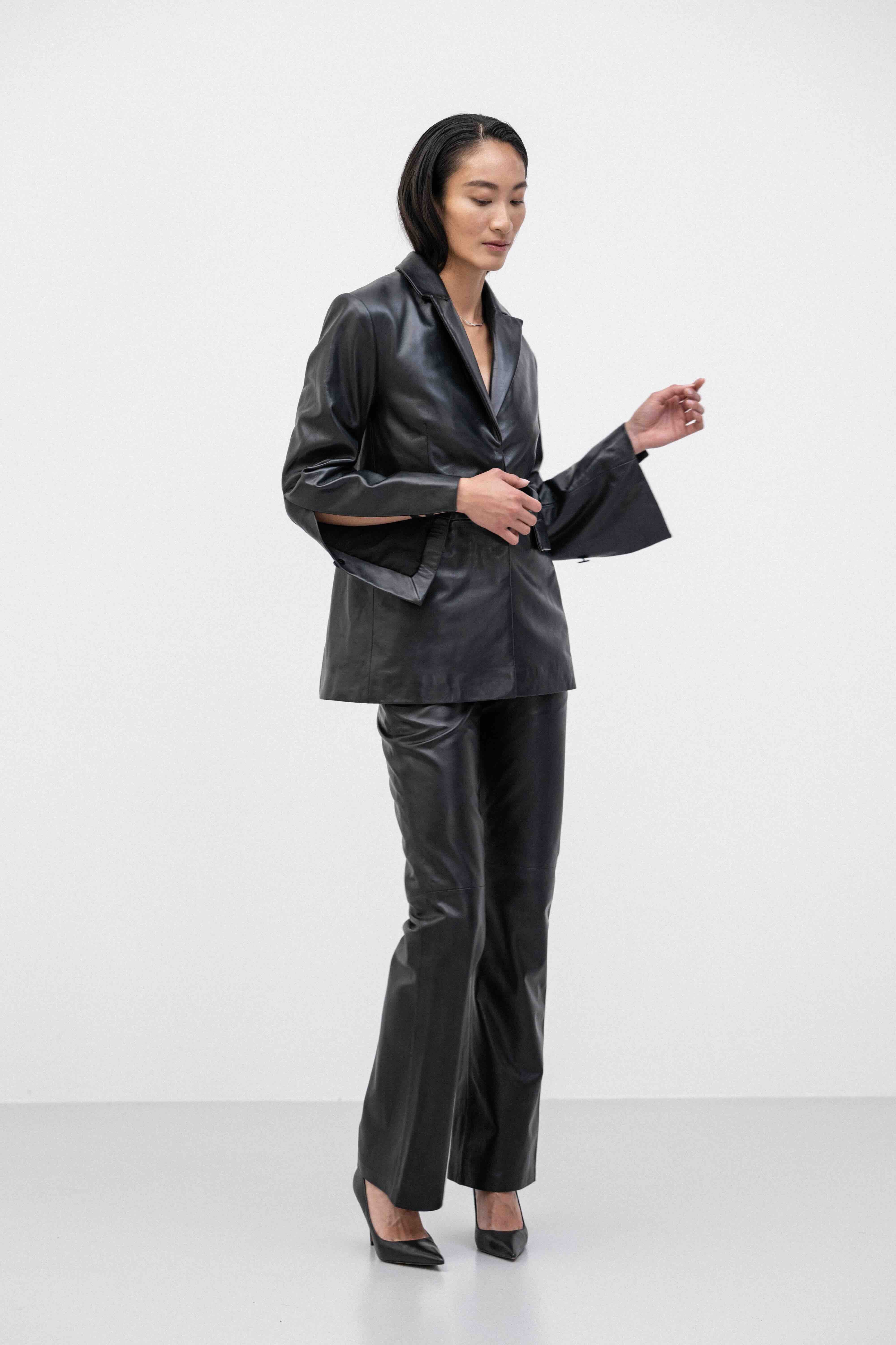 Woman wearing a black buttery-soft breathable lamb leather jacket with lining and black straight lamb leather pants