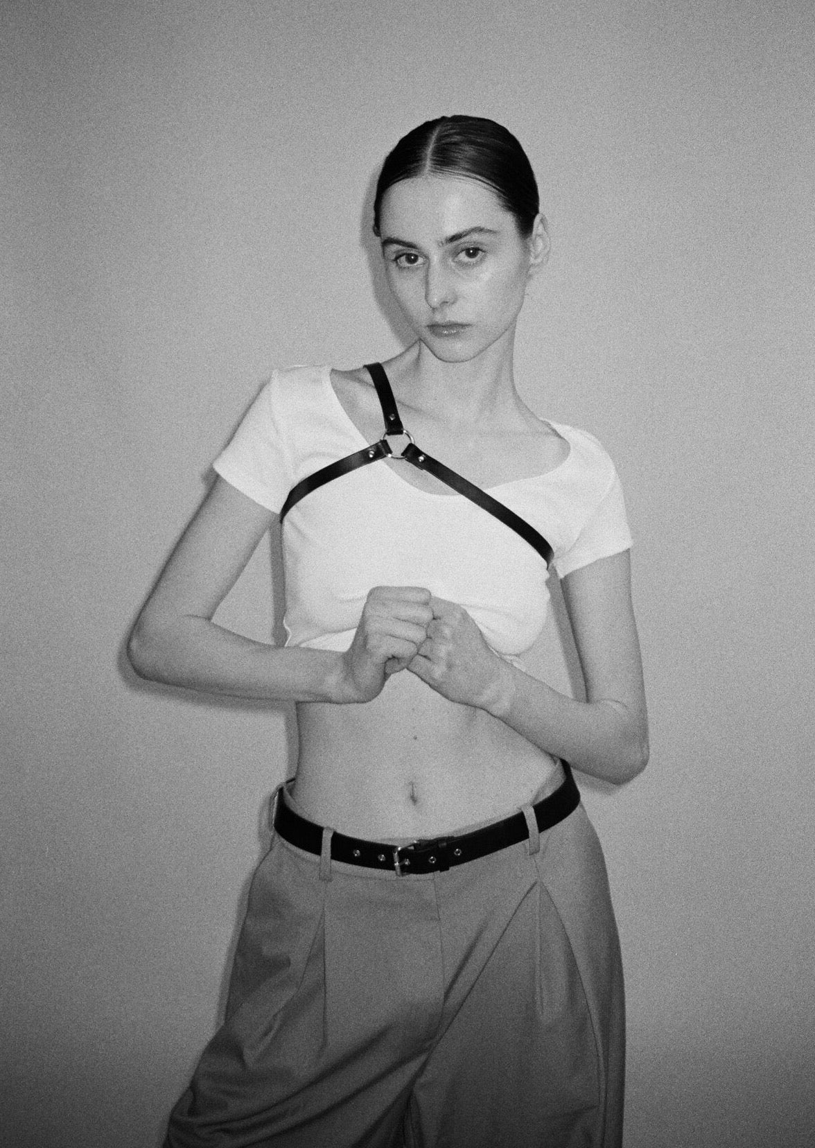 female model wearimg yvy leather asymmetric shoulderpiece in black over white crop top