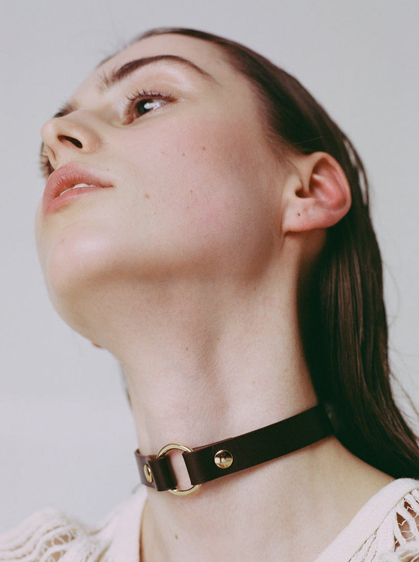 closeup of woman wearing yvy dark brown leather ring choker with gold hardware