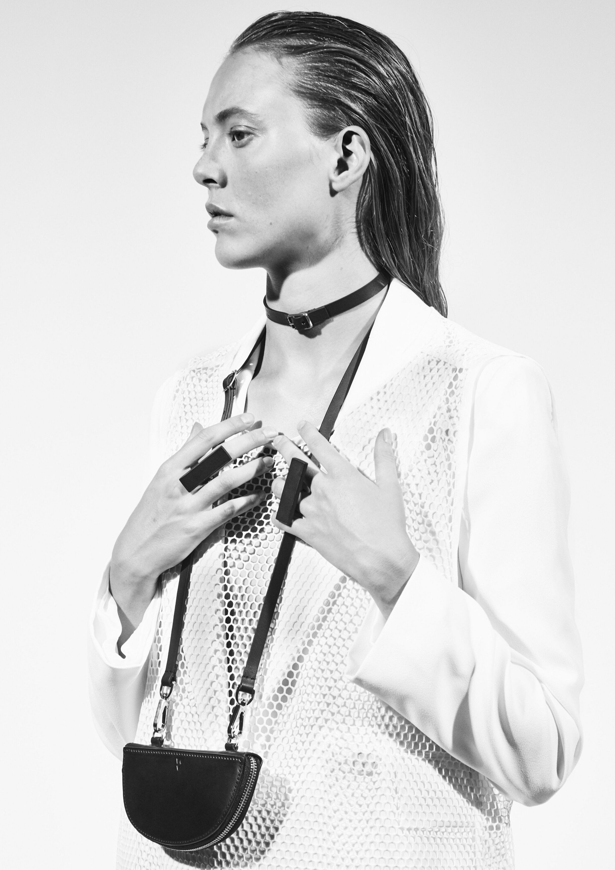 a woman wearing yvy leather rectangle rings, minimalist leather strap choker and half moon pouch 